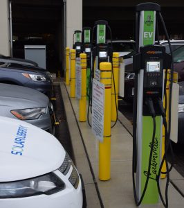 Row of cars hooked up to EV chargers in parking lot