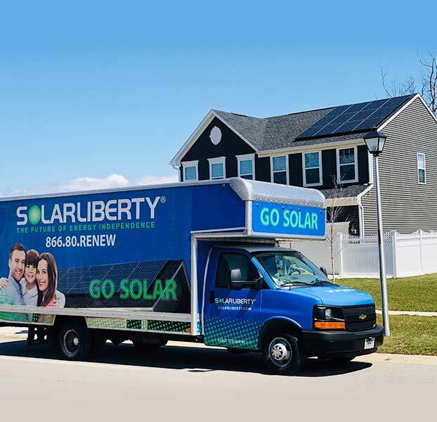 Company van in front of house with solar panels on roof