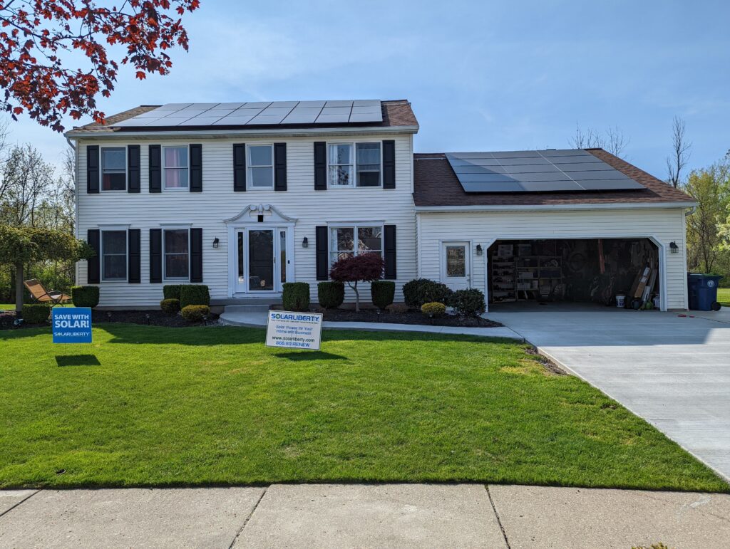 Street view of a white house with an attached garage and a pitched-roof solar array